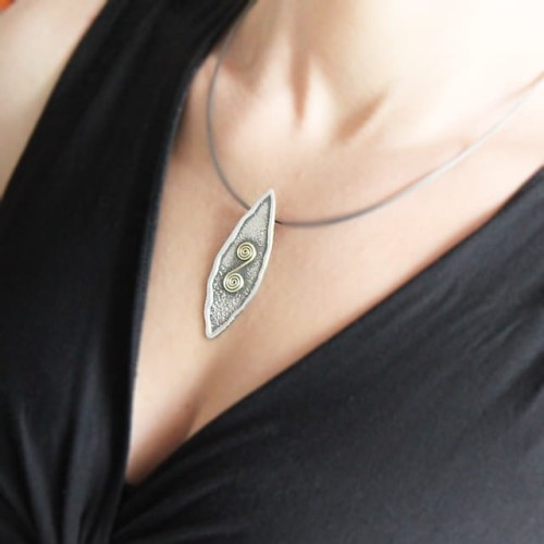 Modelka w czarnej bluzce prezentuje naszyjnik srebrny oksydowany ze ślimaczkiem z mosiądzu – zawieszka subtelnie układa się na dekolcie