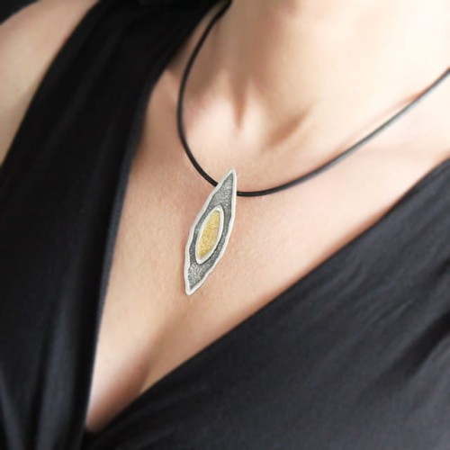 Naszyjnik srebrny oksydowany w kształcie łezki z elementem pozłacanym – prezentacja na dekolcie modelki