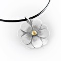 Srebrny naszyjnik z zawieszką w kształcie kwiatka i pozłacaną kuleczką w środku.