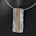 Naszyjnik srebrny handmade na szyi modelki, prostokątna zawieszka z pionowymi liniami w miedzi i mosiądzu
