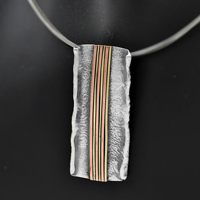 Naszyjnik srebrny handmade na szyi modelki, prostokątna zawieszka z pionowymi liniami w miedzi i mosiądzu