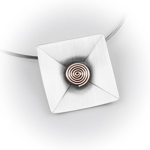 Zbliżenie zawieszki – ciemne oksydowane centrum z miedzianym ślimaczkiem, jasna satynowa powierzchnia zewnętrzna